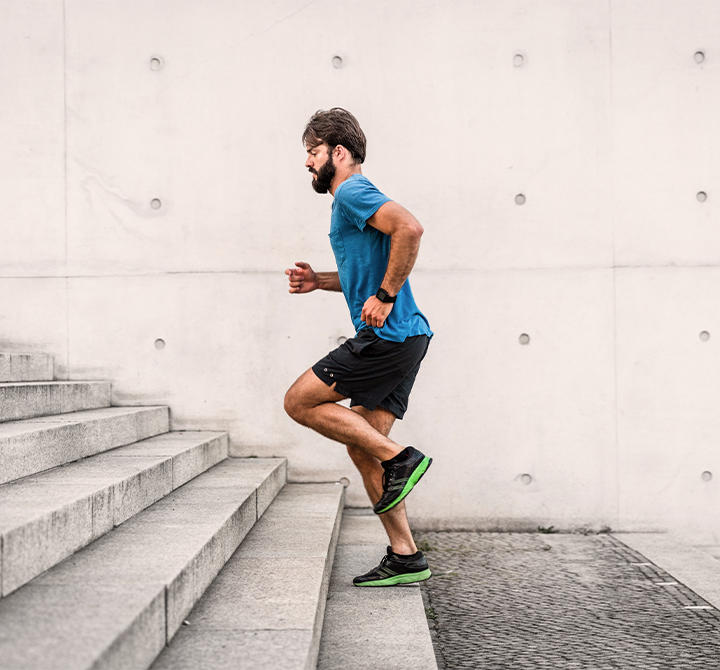 Sporty man running up steps in urban setting